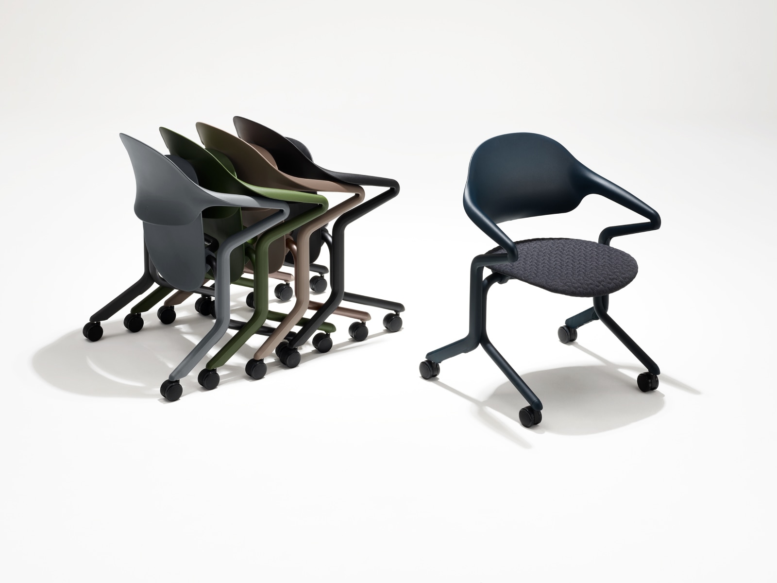 Vier Fuld Nesting-stoelen in verschillende kleuren en afwerkingen in een groep genest naast een afzonderlijke Fuld Nesting-stoel in Nightfall met 3D Knit-textiel.